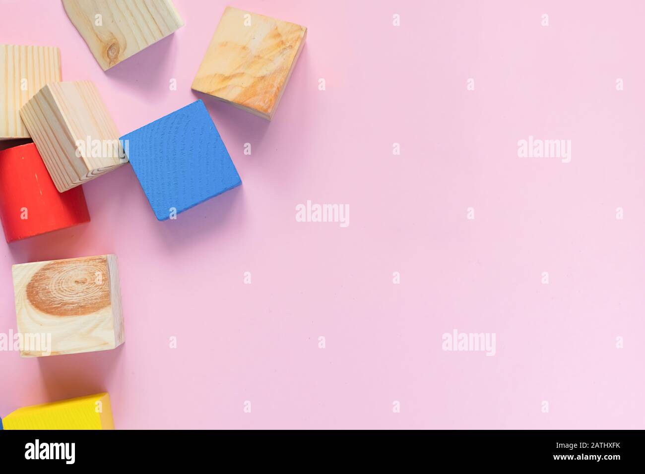 Juguetes de madera para niños sobre un concepto de fondo rosa cero al oeste. Marco de cubos de colores en desarrollo. Espacio de copia. Diseño plano de vista superior. Foto de stock