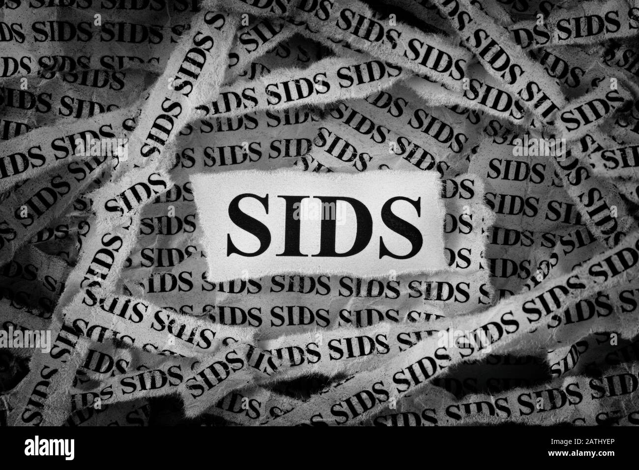 Tiras de periódico con SIDS mecanografiados en ellos (Síndrome De muerte Infantil Repentina). Blanco y negro. Primer plano. Foto de stock