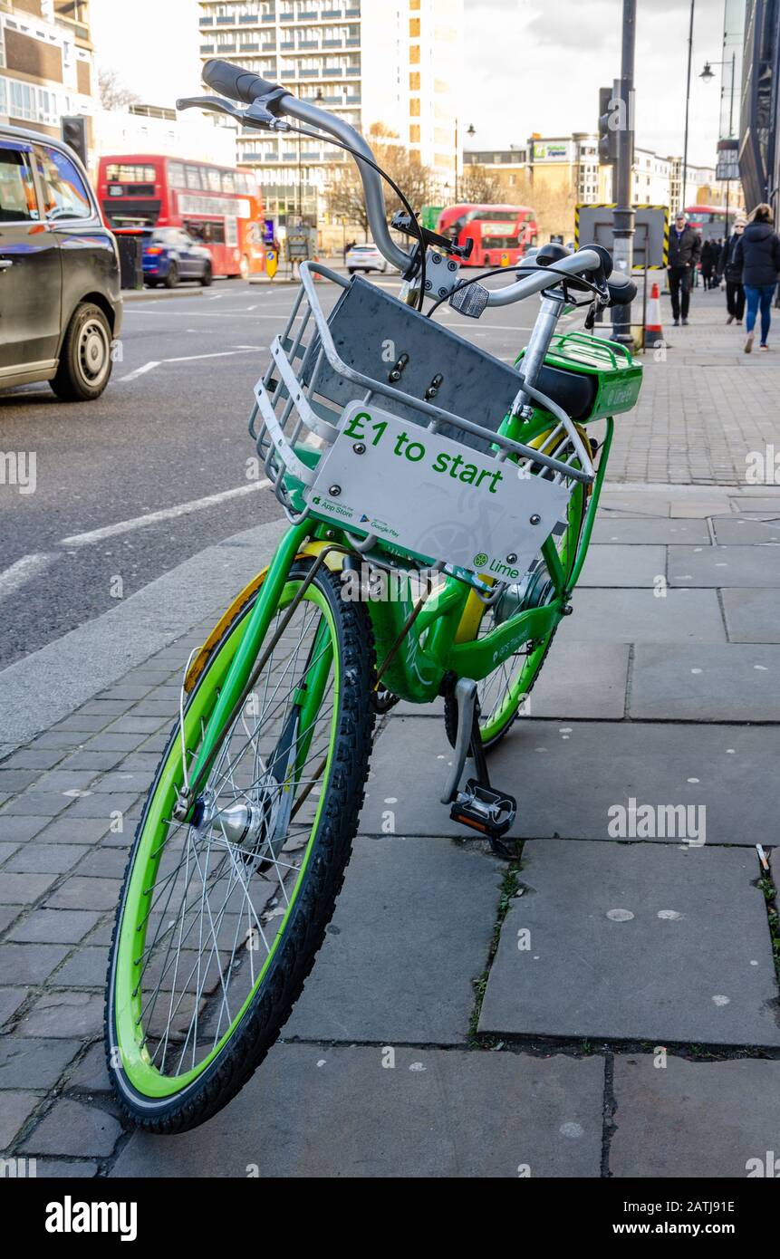 Una bicicleta de alquiler electrónica Lime-e en su soporte en un pavimento en Londres, Reino Unido Foto de stock
