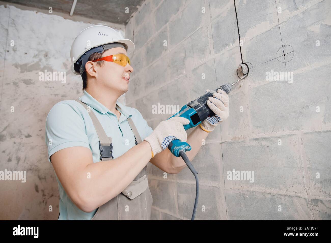 Man con perforador de martillo con corona de diamante haciendo agujero en pared cable eléctrico, toma, interruptor Fotografía de stock - Alamy