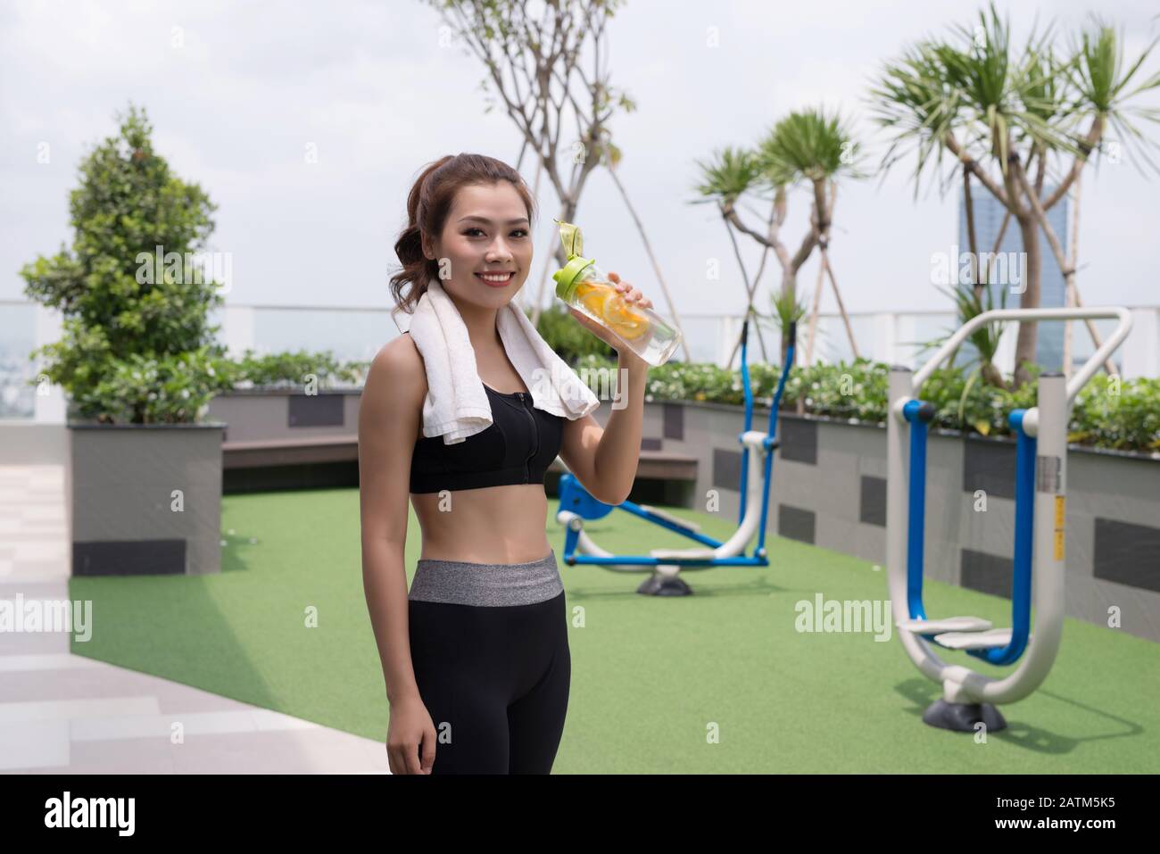 Hermosa joven asiático mujer alegre y beber agua después de hacer ejercicio, el ejercicio al aire libre y un estilo de vida saludable conceptos Foto de stock
