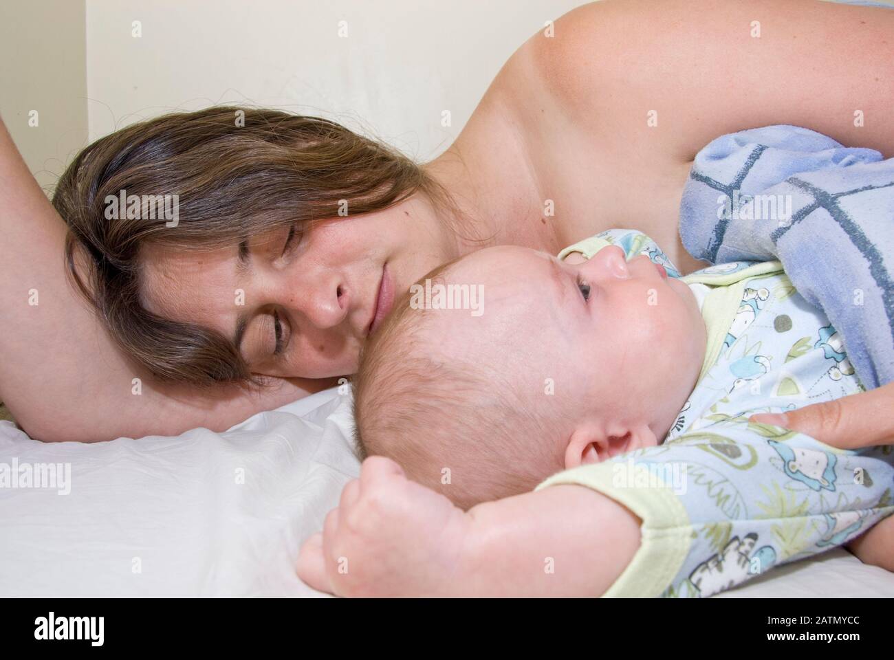 Baby Boy y Madre despertando del sueño abrazados en Mummy's Bed Foto de stock