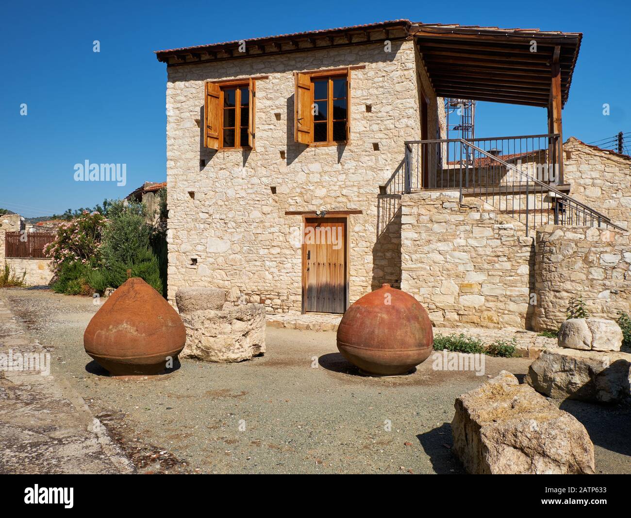 Casa de piedra tradicional con ánforas de vino de barro volteadas en el patio. Pueblo lania. Limassol. Chipre Foto de stock