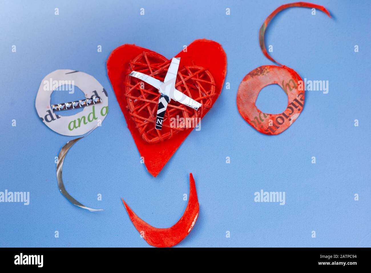 Concepto de amor por la vida fija para el día de San Valentín - OXO y papel rojo corazón y boca sonriente sobre un fondo azul claro. Copyspace. Foto de stock