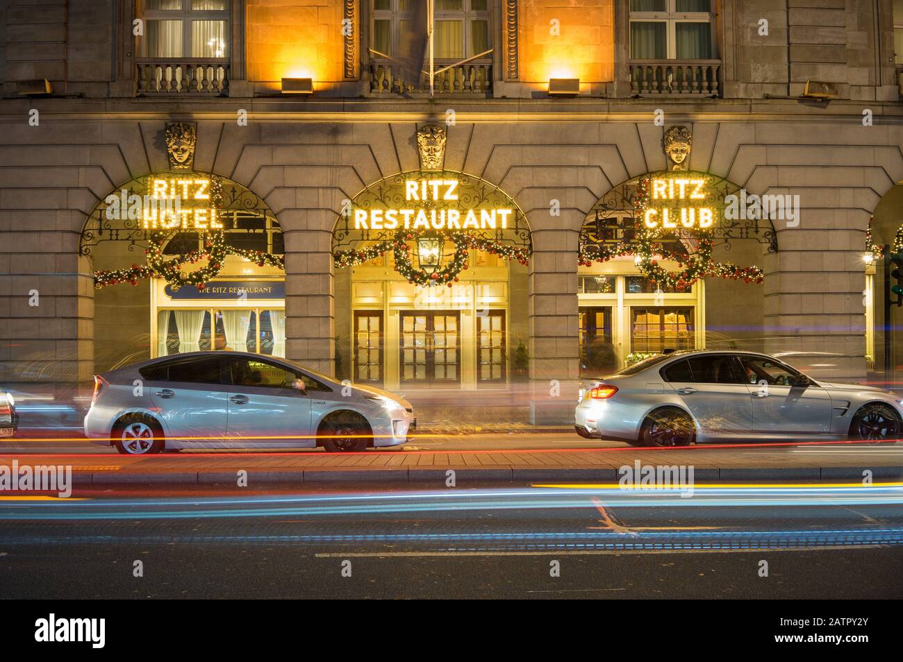 El Hotel Ritz y el Restaurante se iluminaron por la noche con decoraciones navideñas colgando. Exposición prolongada con las luces de los coches que pasan delante. Londres Foto de stock