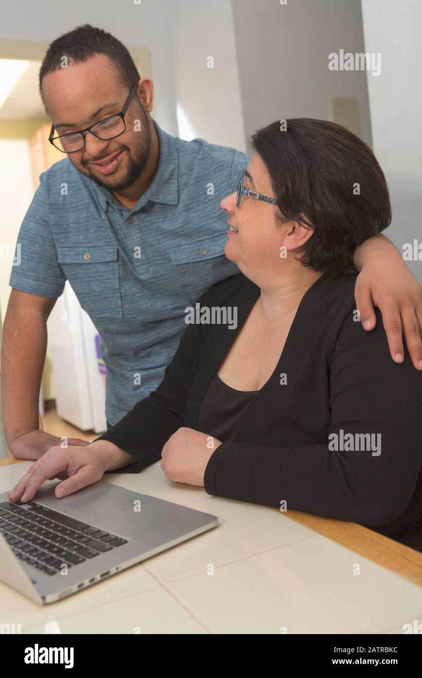 Madre e hijo adulto joven en casa usando un ordenador portátil Foto de stock