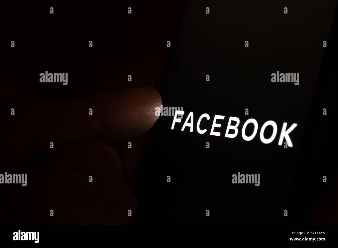 Nuevo logotipo de la empresa Facebook en la pantalla oscura y con el dedo a punto de tocarlo. Foto conceptual. Foto de stock