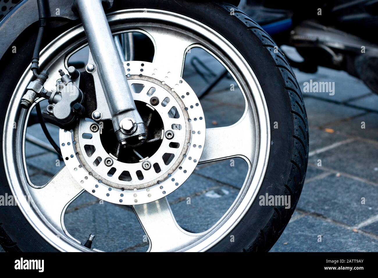 Detalle de primer plano de la rueda delantera de una motocicleta de  carreras. Se trata de la pinza de freno, el rotor, la llanta, el neumático  y la suspensión. Primer plano Fotografía