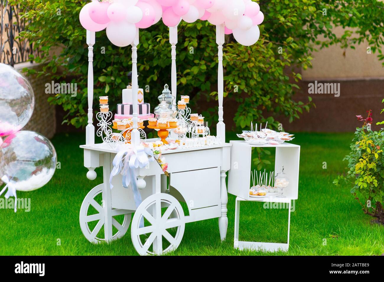 Candy Bar. Carrito de madera blanca con dulces decorados con globos en  hierba verde Fotografía de stock - Alamy