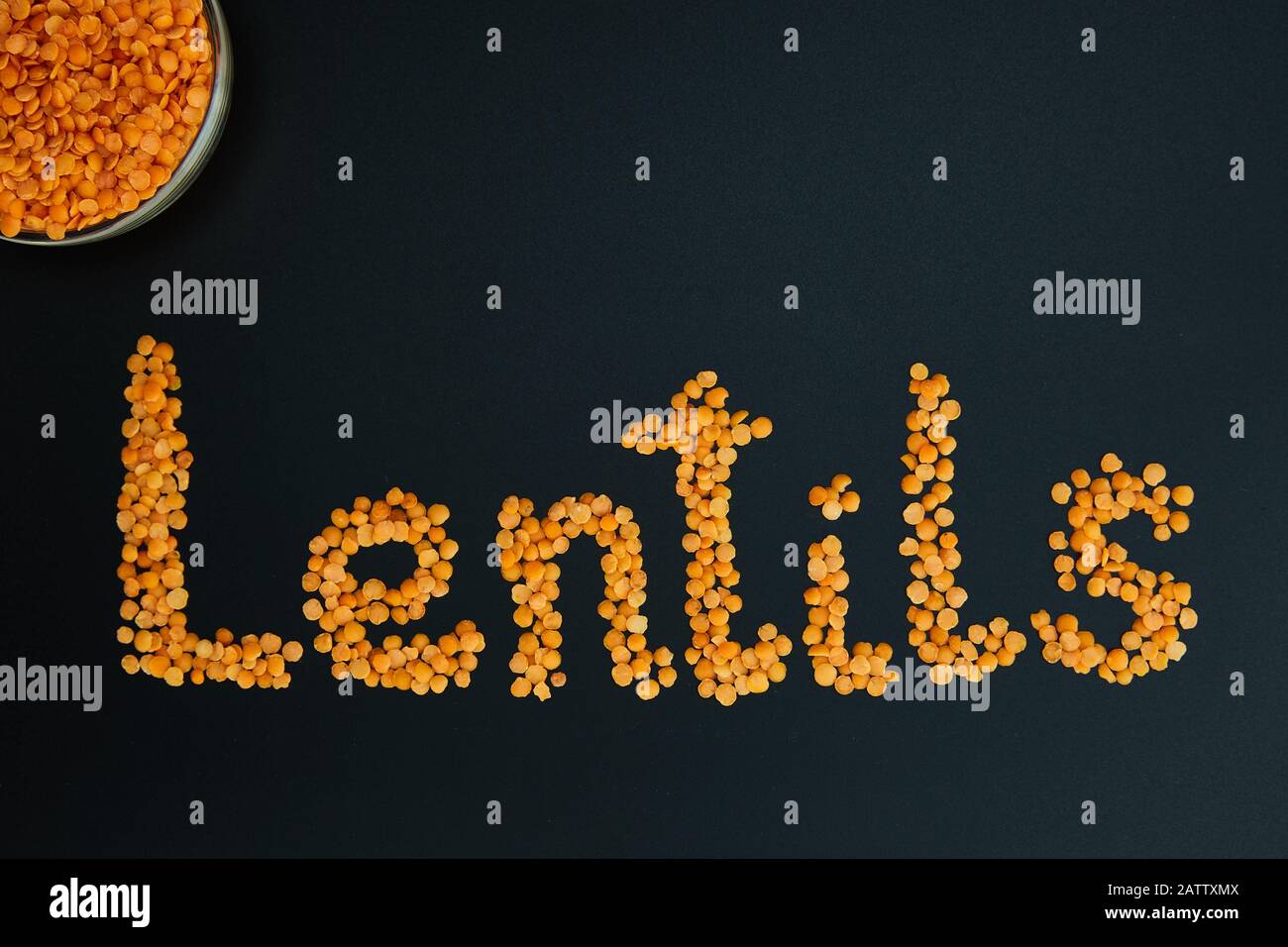 Lentejas rojas sobre fondo negro. Laico plano. La palabra "lentejas" en