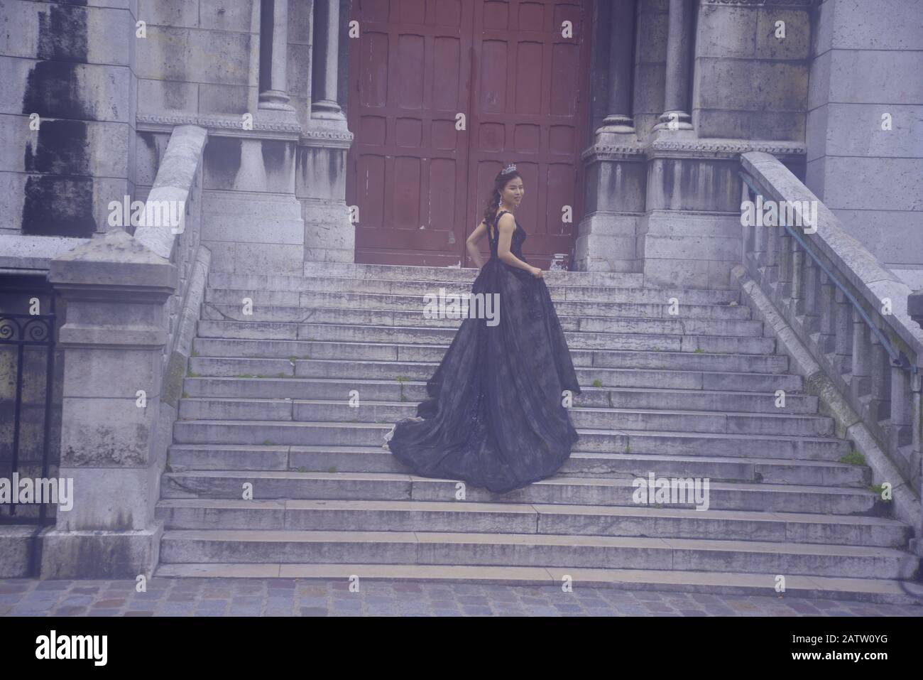 Mujer asiática con un largo vestido negro en una escalera en París, pasakdek Foto de stock