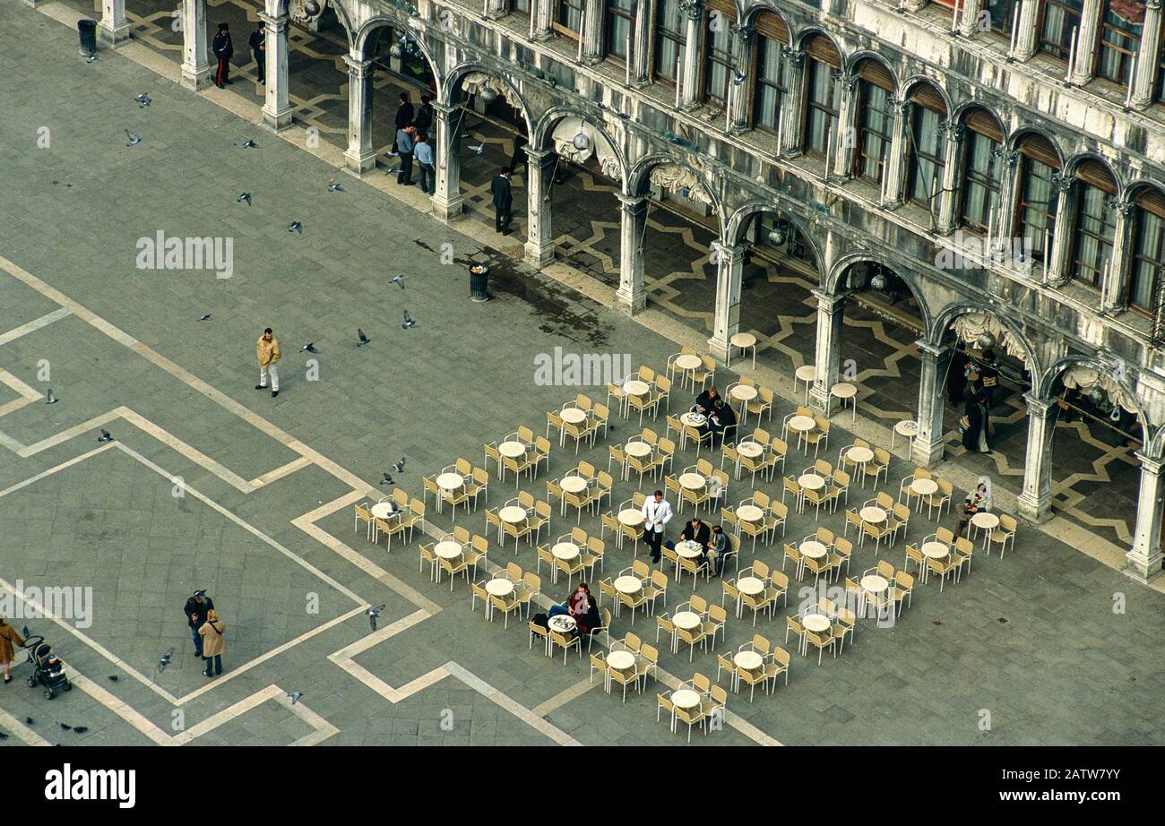 Vista Hacia Abajo En Una Tranquila Plaza De San Marcos (Piazza San Marco), Venecia. Mesas de restaurante, edificio Histórico y Detalle de baldosas con Pocos Turistas. Foto de stock