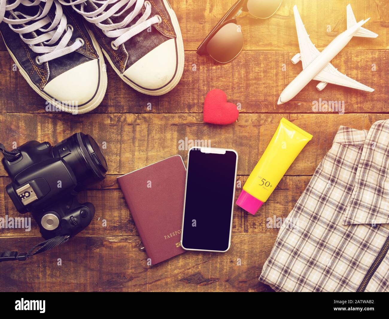 Plano de laicos pasaporte ,móvil, modelo de avión , zapatillas , Monedero cámara y elementos accesorios del viajero sobre fondo de madera con copia un viaje espacial. Foto de stock