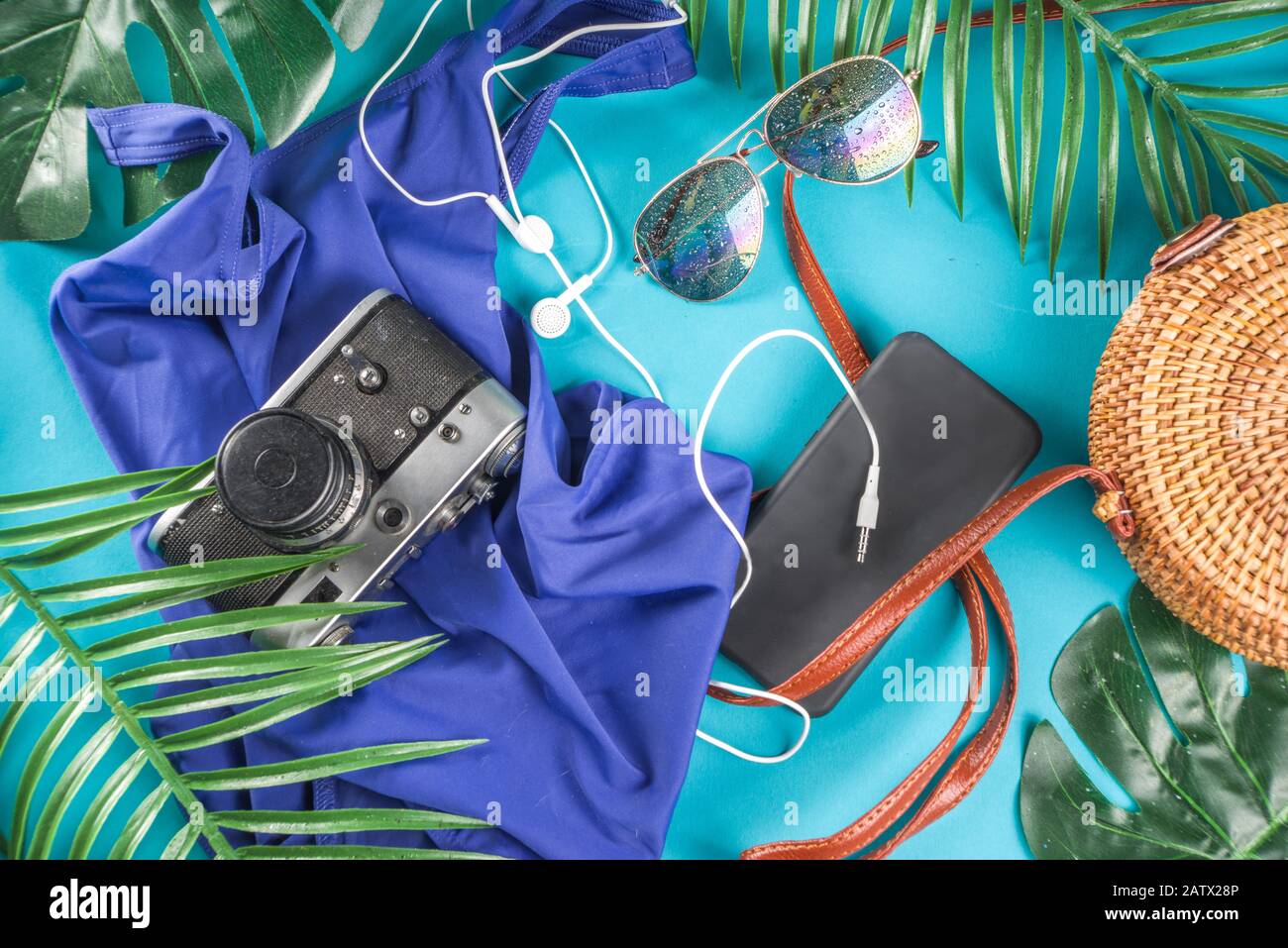 Vacaciones de verano y concepto de viajes. Accesorios de playa cosas -  bolsa, sombrero, traje de baño, gafas de sol, cámara, hojas tropicales en  aguamarina, azul turquesa b Fotografía de stock - Alamy