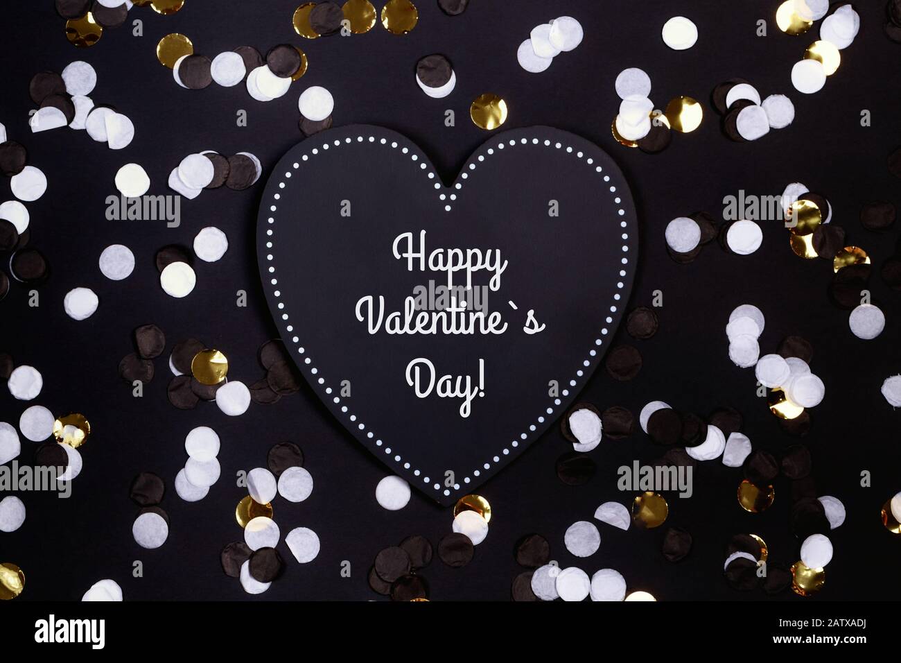 Confeti y corazón negro en el fondo negro, día de San Valentín, amor. Foto de stock