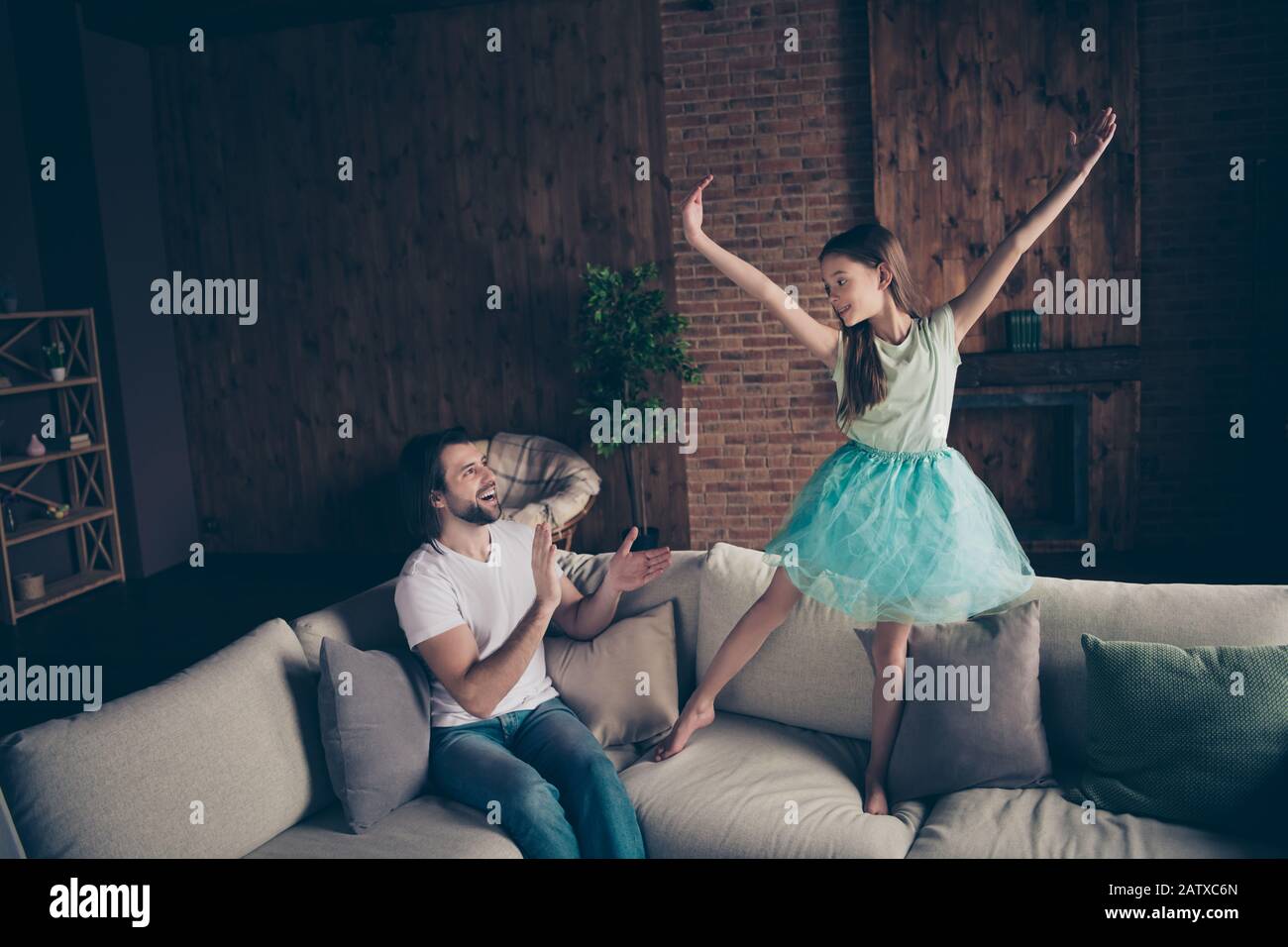 Foto de la pequeña dama encantadora muy enérgica guapo mirando a la hija rendimiento de baile de la escuela sentado sofá aplaudiendo los brazos sala de ovación casa Foto de stock