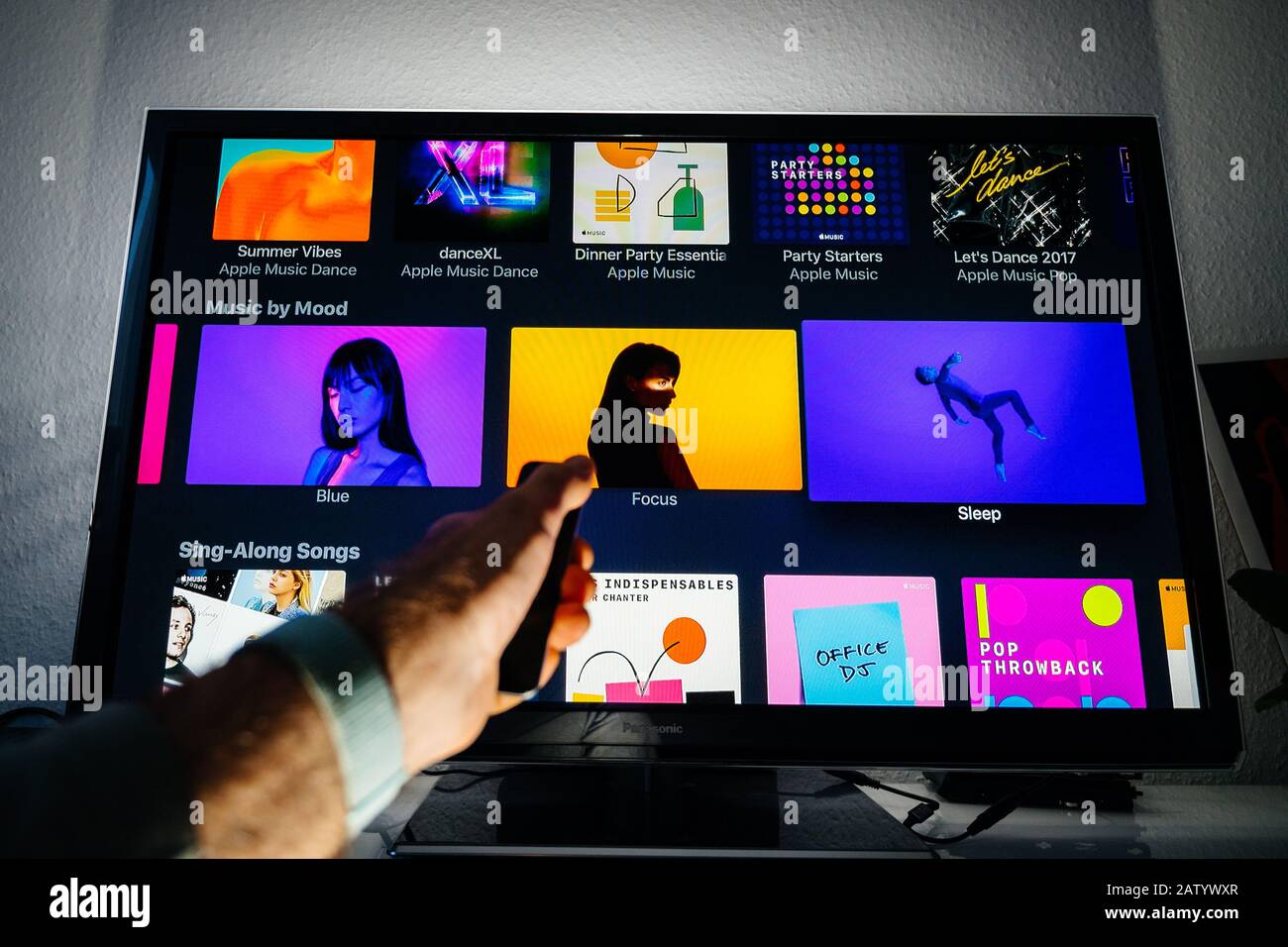 París, Francia - Circa 2019: Hombre mano mando a distancia de Apple TV  frente a Panasonic plasma tv en sala de estar con música por humor lista de  reproducción en Apple Music