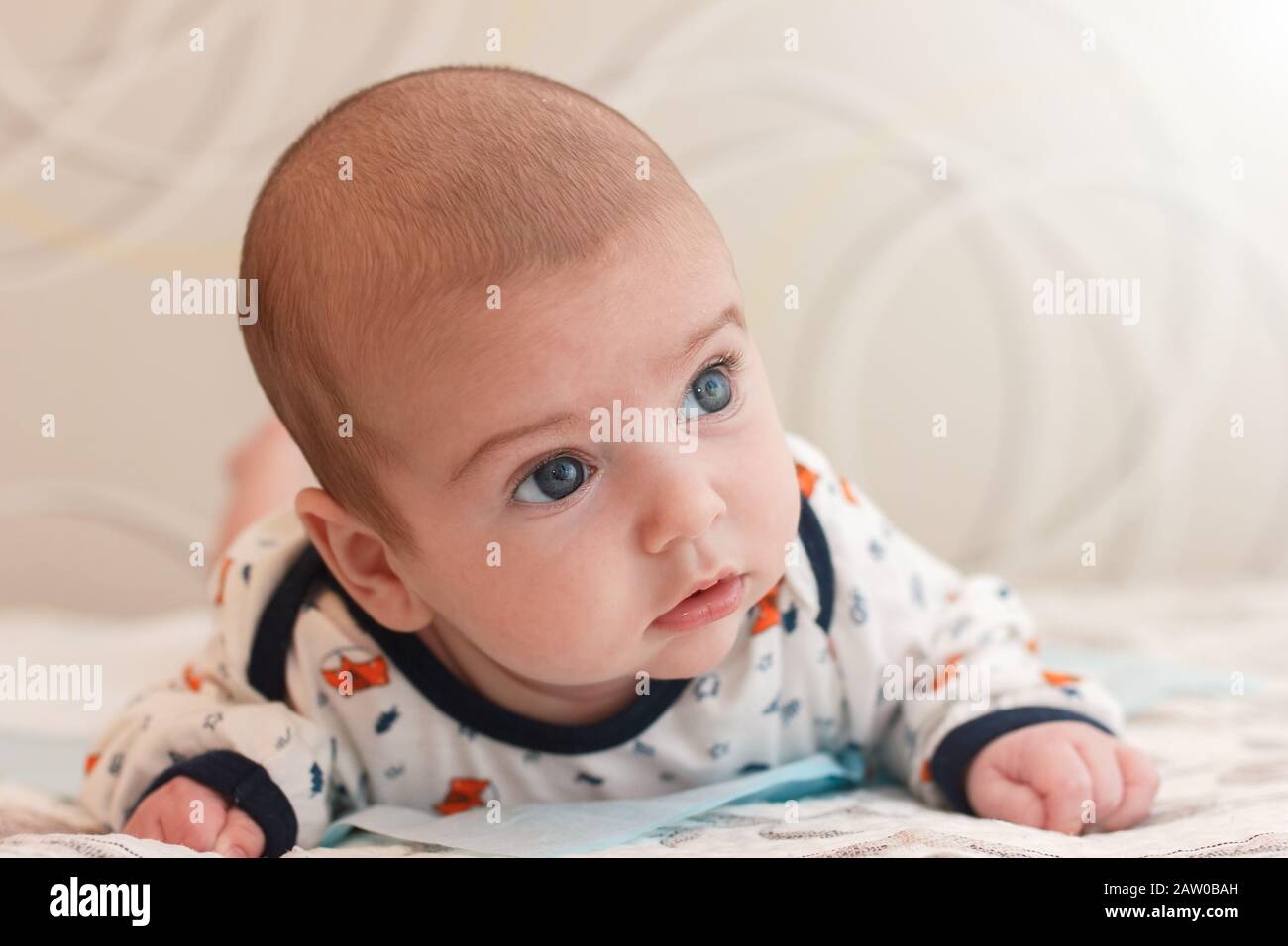 retrato de un adorable bebé de 2 meses de edad con ojos azules grandes y  pestañas largas. lindo bebé acostado en el estómago y mira con sorpresa  Fotografía de stock - Alamy