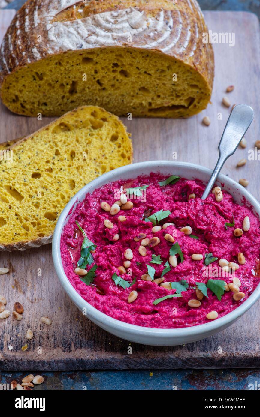 Humus casero de remolacha asada y pan de masa de calabaza en un fondo de pizarra Foto de stock