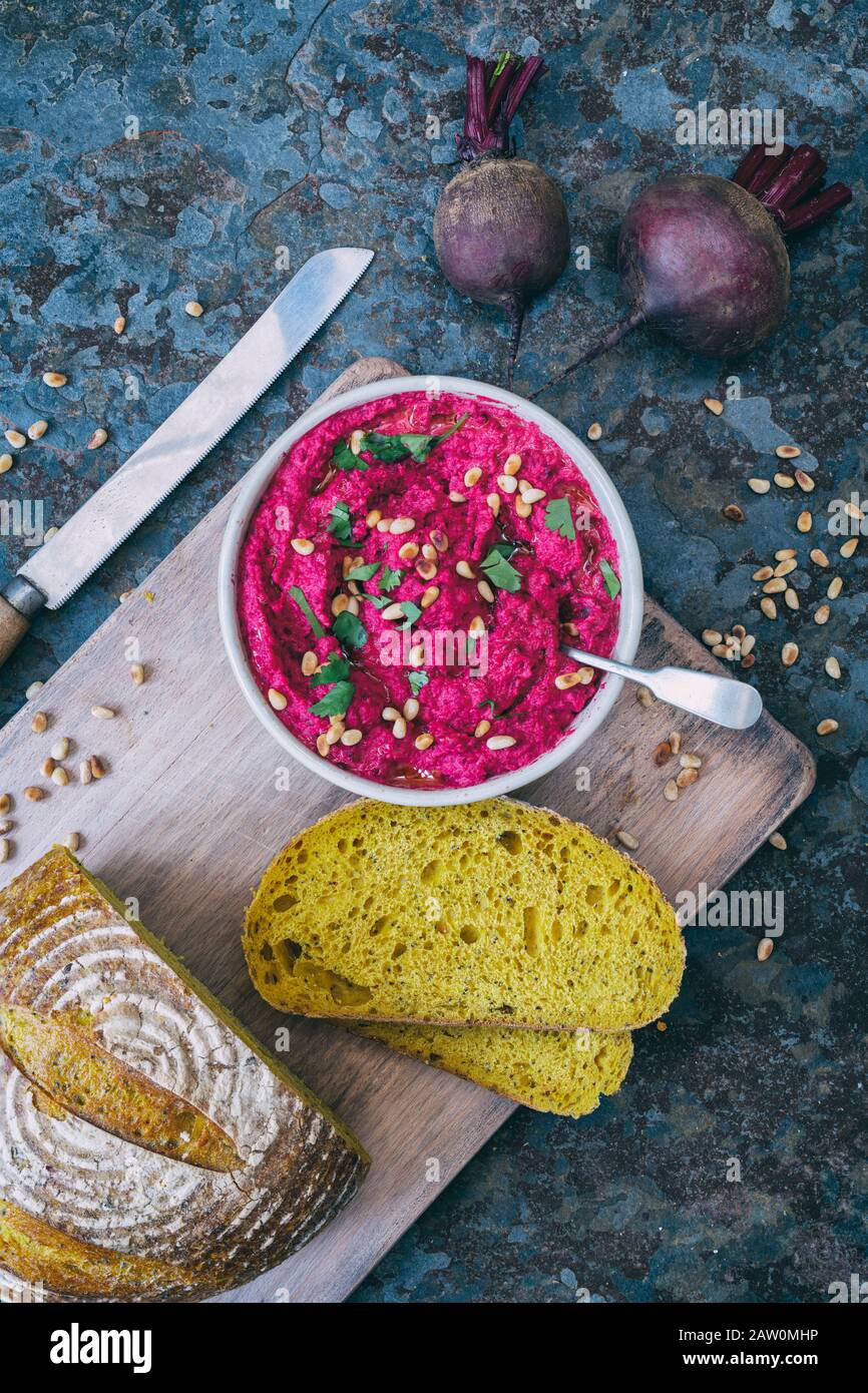 Humus casero de remolacha asada y pan de masa de calabaza en un fondo de pizarra Foto de stock