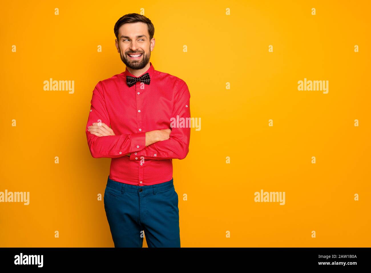 Foto de atractivo hombre de negocios brazos cruzados amable persona mirando lado espacio vacío ropa con estilo camisa roja con lazo negro corbata azul pantalones aislados Fotografía de -