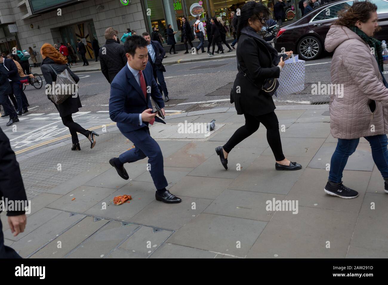 Los peatones evitan un alevar de fideos y salsa, dejados y descartados en  el pavimento durante la hora del almuerzo en el distrito financiero de la  capital, el 4 de febrero de
