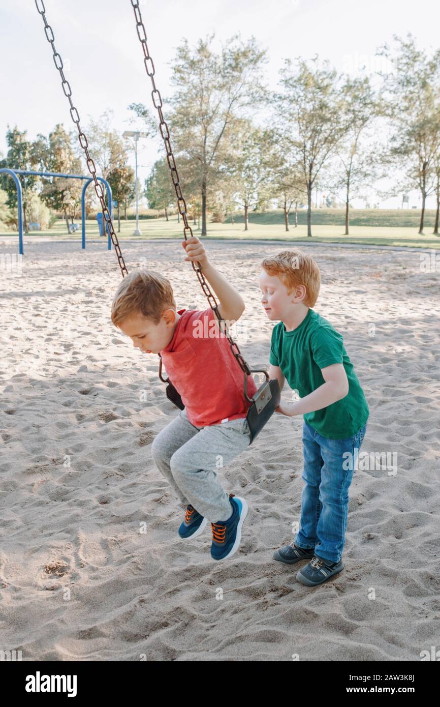 Two boys playing on swings fotografías e imágenes de alta resolución - Alamy