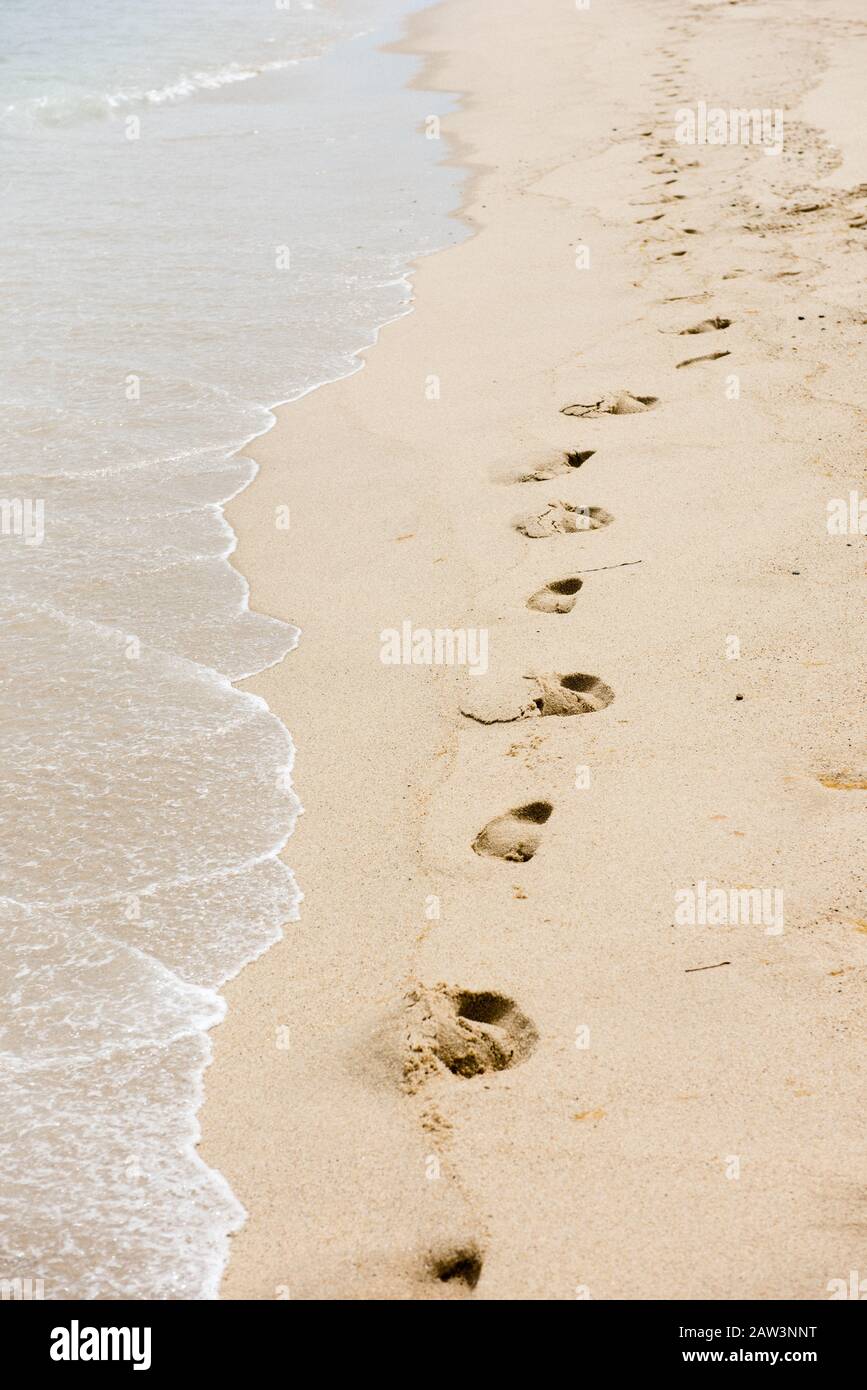Huellas en la arena a lo largo de una playa aislada Foto de stock