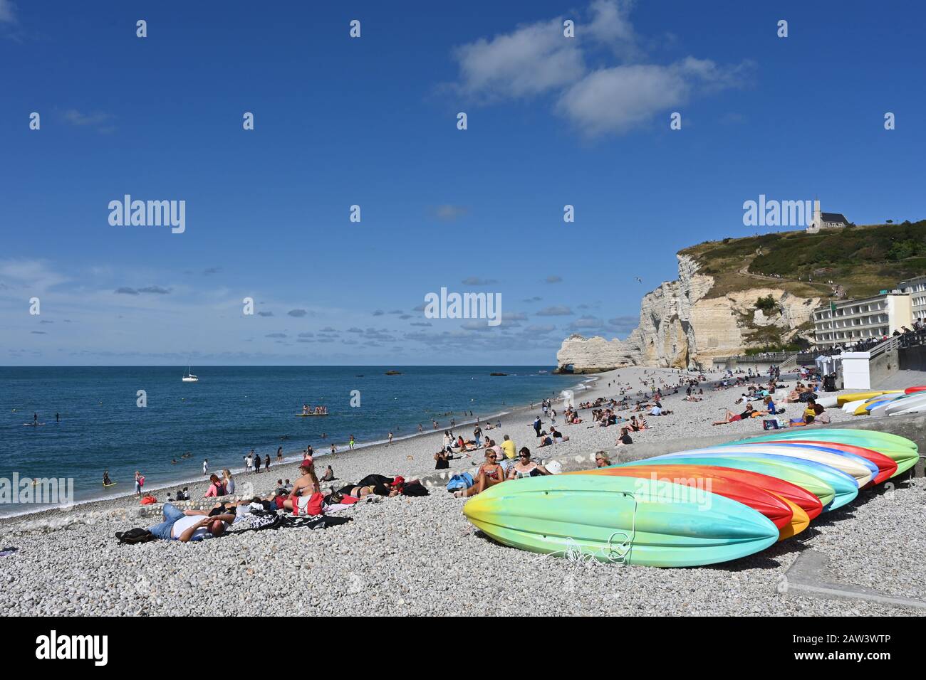 Turistas disfrutando del buen tiempo en la playa de Etretat en Normandía, Francia. Foto de stock