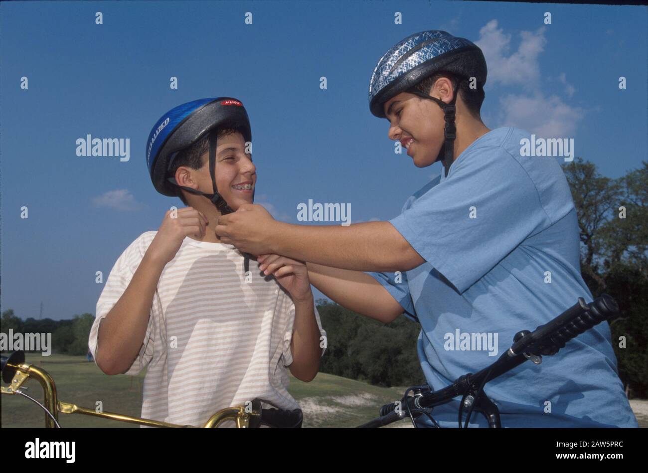 Los niños de 13 años ajustan las correas del casco antes de montar en bicicletas de montaña en Austin, Texas. Foto de stock