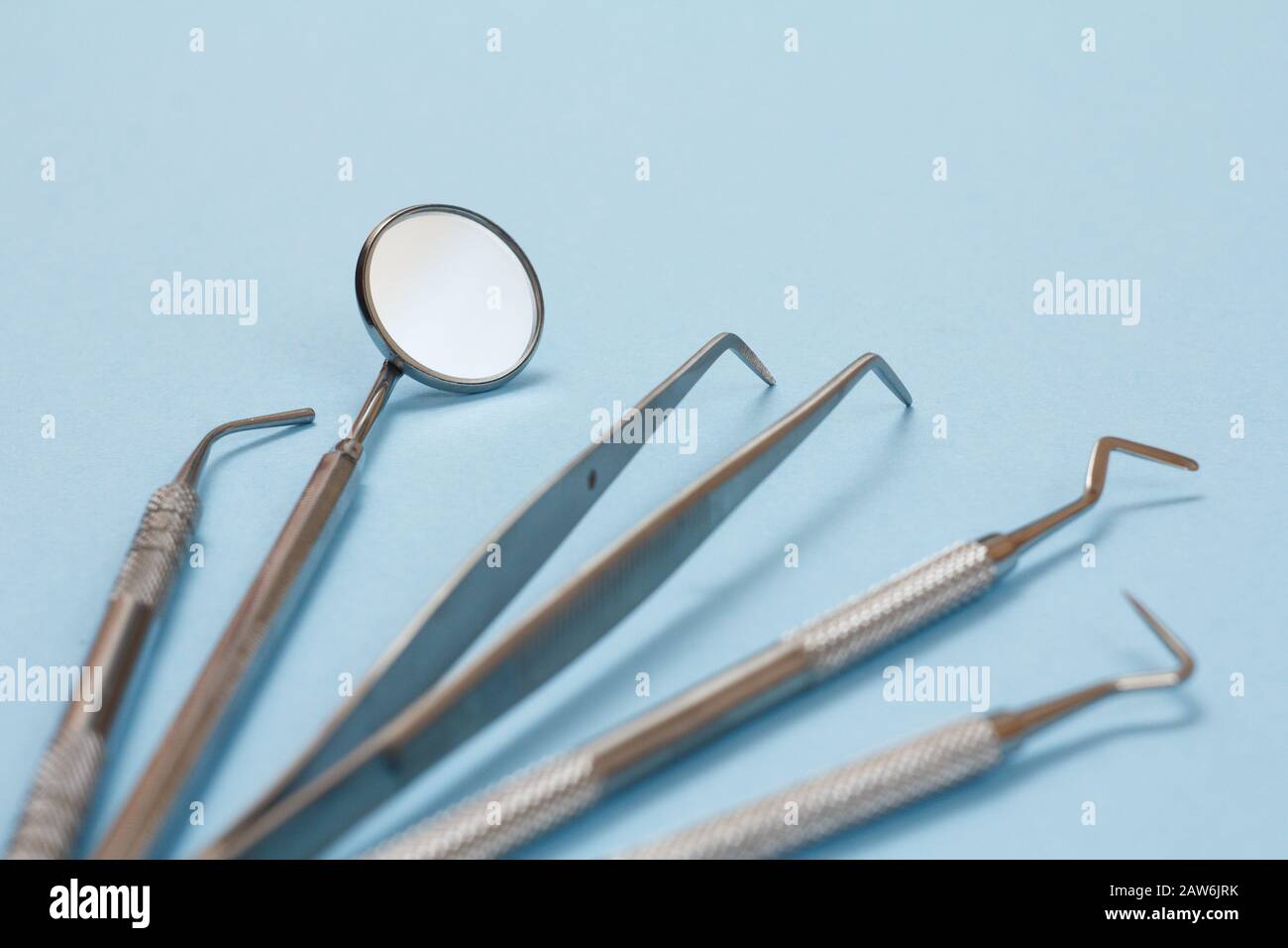 Conjunto de instrumentos de relleno compuestos para tratamiento dental. Espejo dental, sonda, pinzas, enchufe y rascador sobre fondo azul. Herramientas médicas. Shal Foto de stock