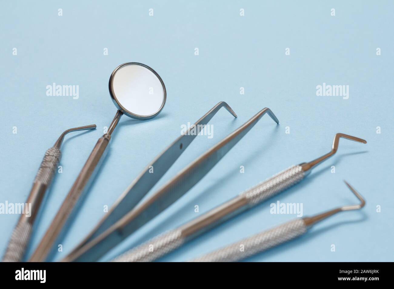 Conjunto de instrumentos de relleno compuestos para tratamiento dental.  Espejo dental, sonda, pinzas, enchufe y rascador sobre fondo azul.  Herramientas médicas. Shal Fotografía de stock - Alamy