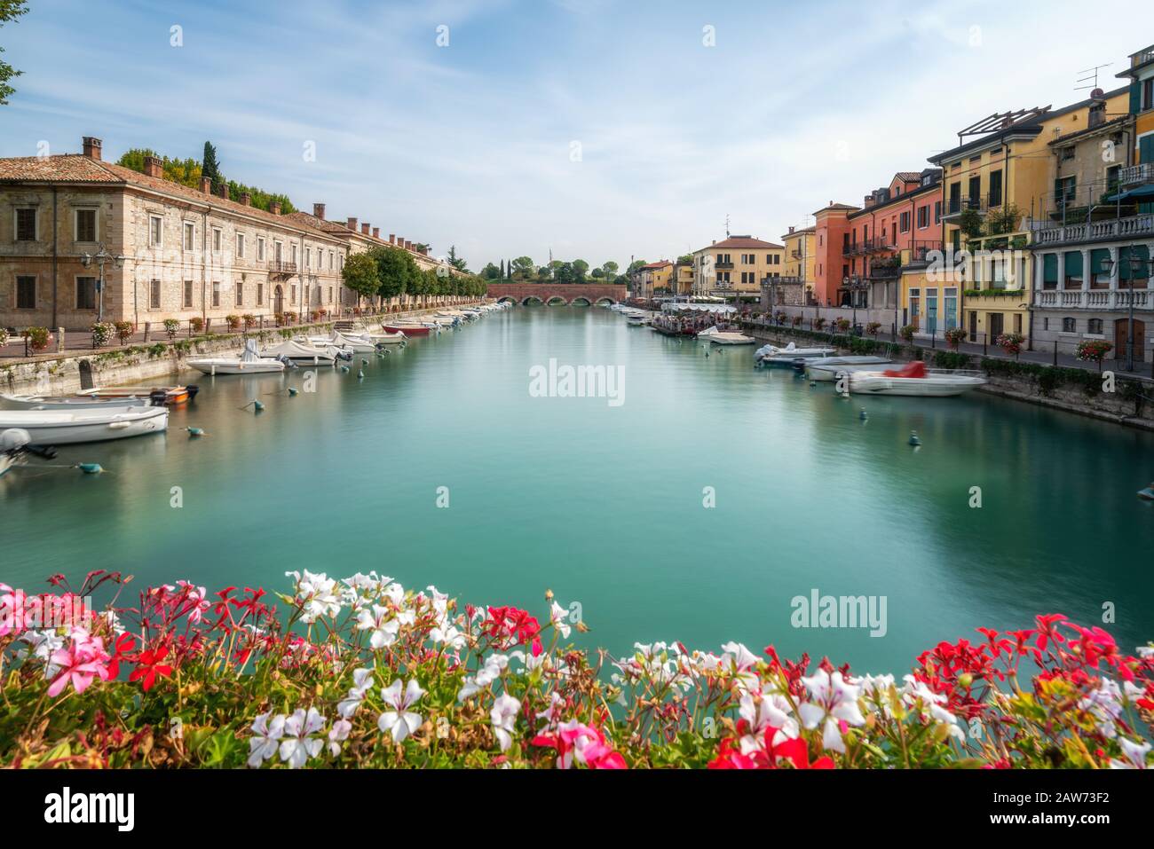 Colorido pueblo de Peschiera del Garda con botes y borrosa geranio flores. La ciudad está situada en el Lago di Garda,al este de Venecia, Italia, Europa. Foto de stock