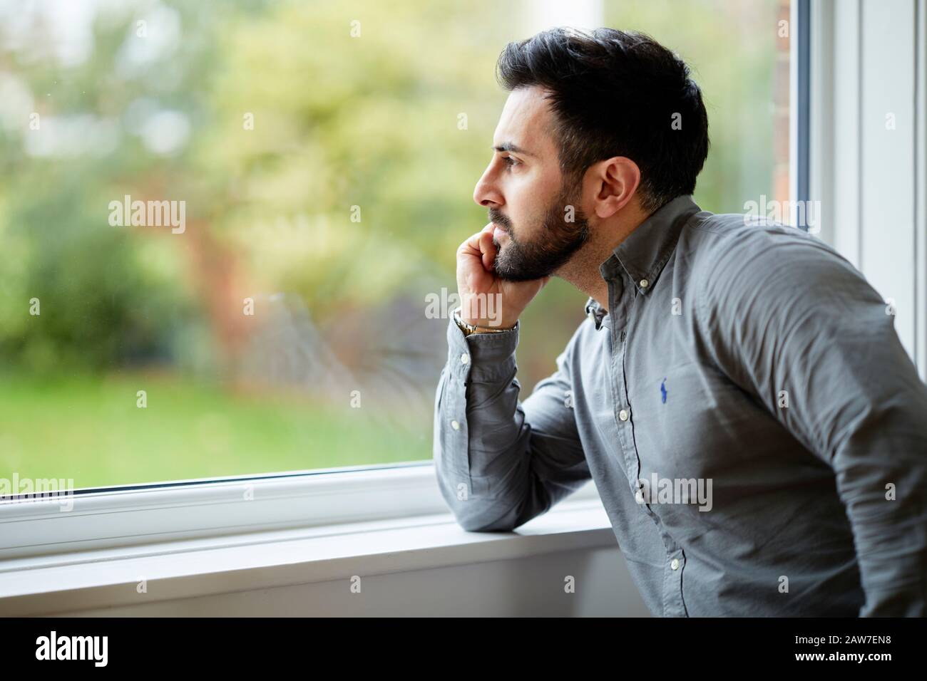 Hombre mirando hacia afuera de la ventana Foto de stock