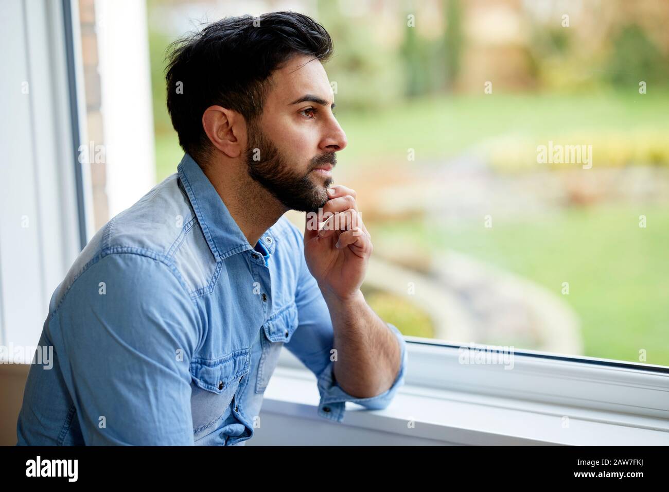 Hombre mirando hacia afuera de la ventana Foto de stock