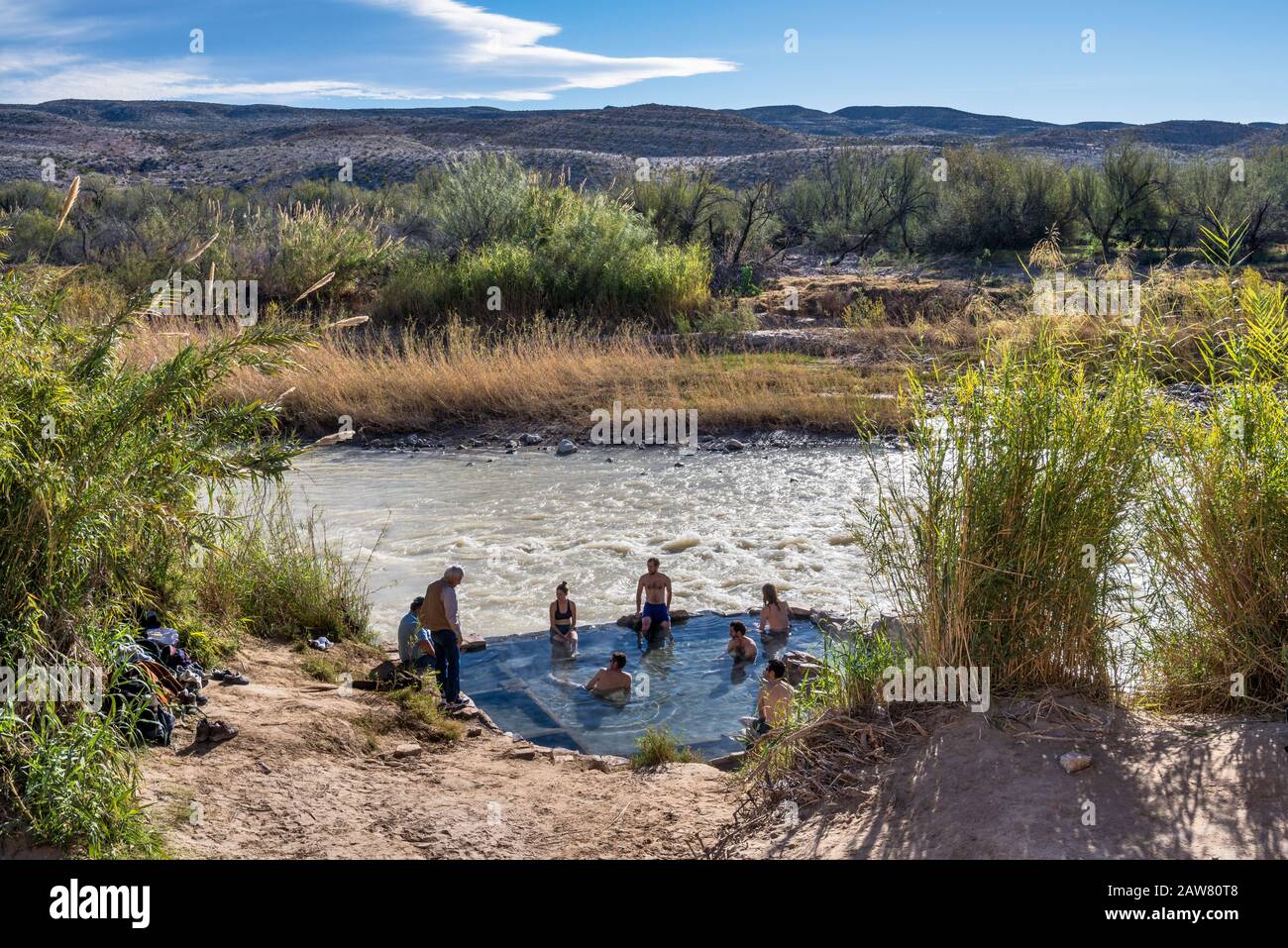 Bañistas en la piscina Hot Springs en el borde de Río Grande, lado mexicano al otro lado del río, Desierto de Chihuahua, Parque Nacional Big Bend, Texas, Estados Unidos Foto de stock