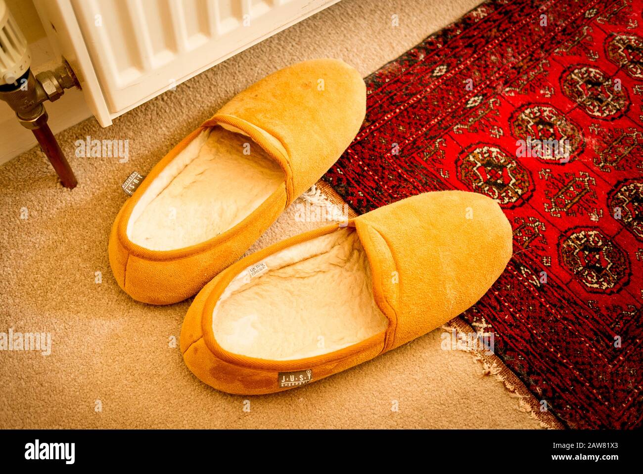 Un par de zapatillas forradas con piel de oveja listas y esperando en una mañana fría en el Reino Unido Foto de stock