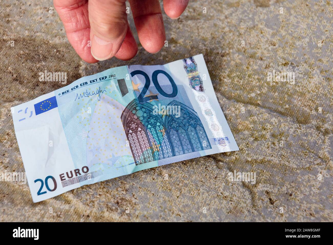 Un anciano afortunado pensionista encuentra dinero en la mano baja para recoger una nota de veinte euros en el piso. Europa Foto de stock
