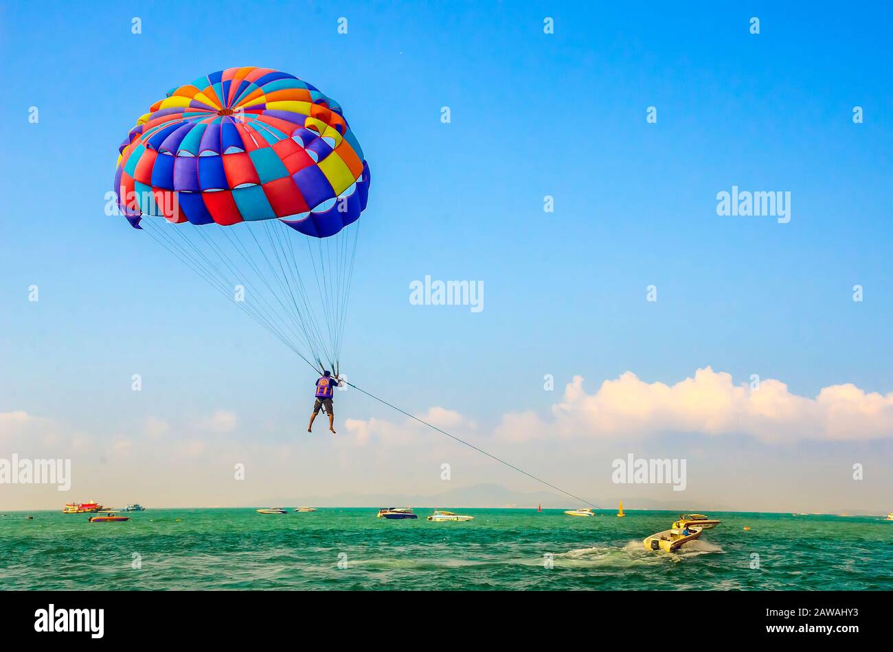 PATTAYA, TAILANDIA – DEC. 21, 2018: Turismo disfrutando de parasailing con paracaidismo colorido en la Isla Coral o en la Isla Koh Larn cerca de Pattaya. Foto de stock
