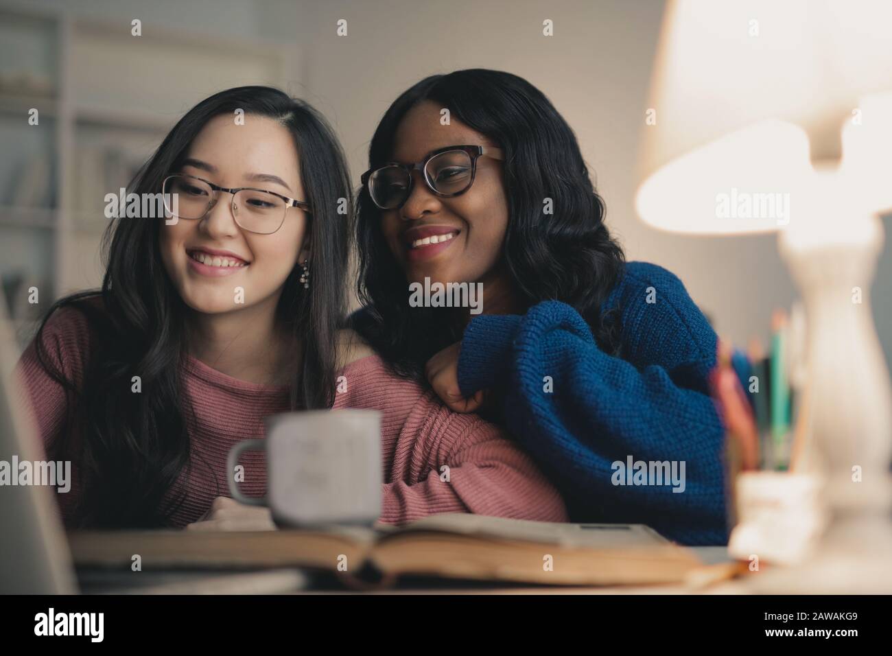 dos mujeres se ríen mirando el portátil Foto de stock