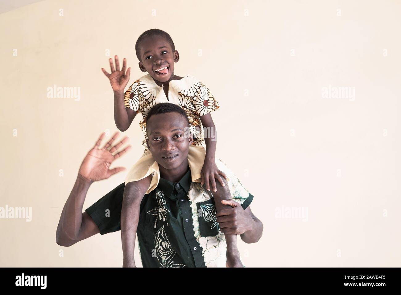 Padre africano y niño posando juntos sonriendo y riendo con lengua en frente de fondo aislado Foto de stock