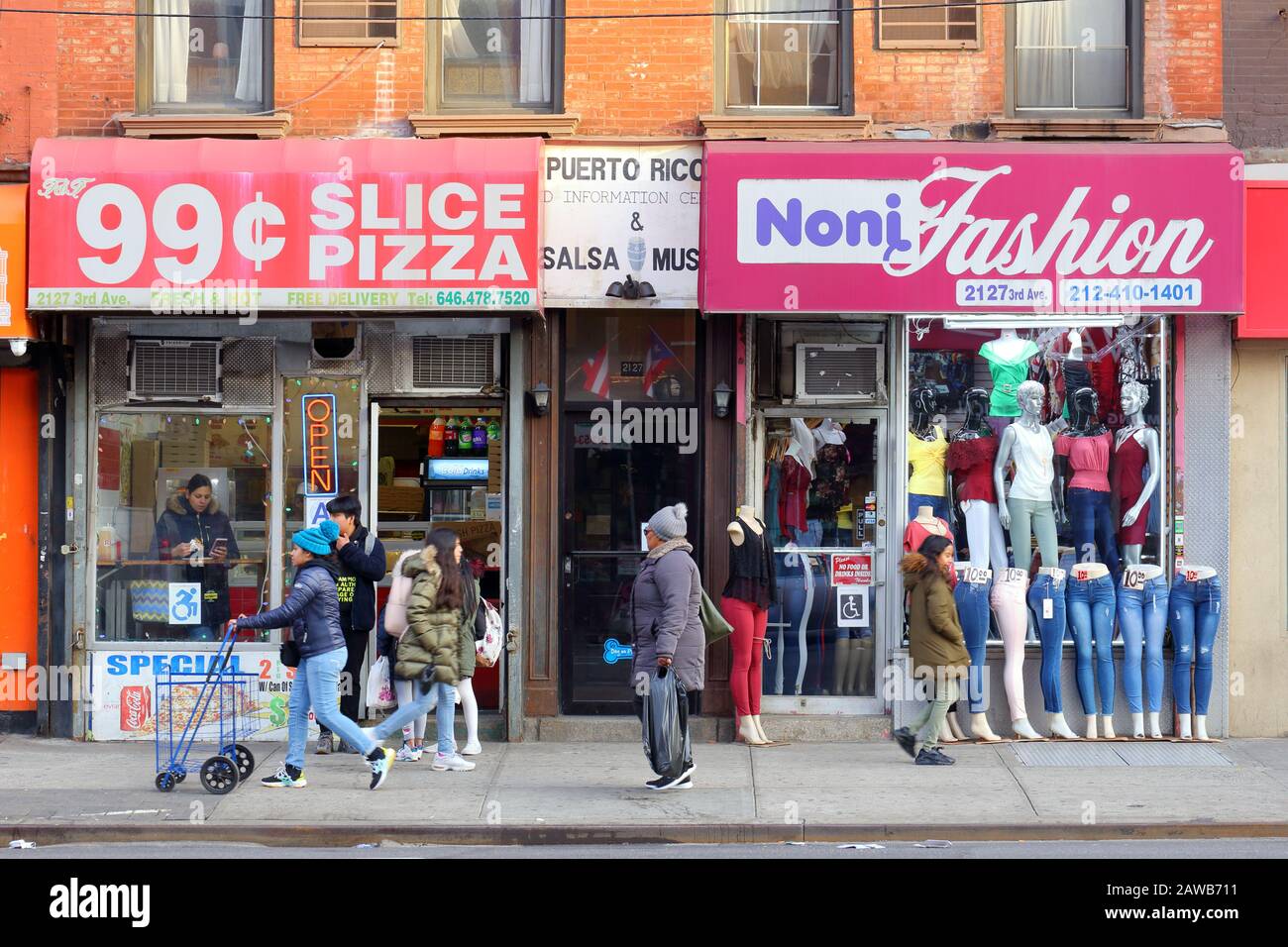 99 Pizza, Noni Fashion, 2127 3rd Ave, Nueva York, NY. Escaparate exterior de una pizzería, y una tienda de ropa en el barrio East Harlem de Manhattan. Foto de stock