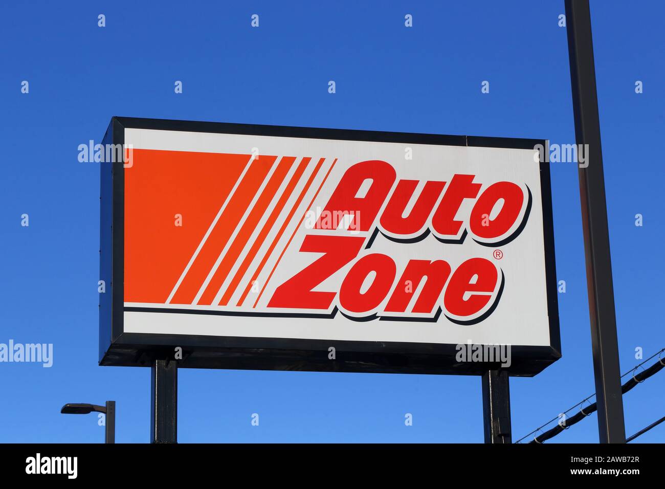 Un distribuidor de piezas de automóvil AutoZone de refacción firma un poste contra un cielo azul soleado Foto de stock