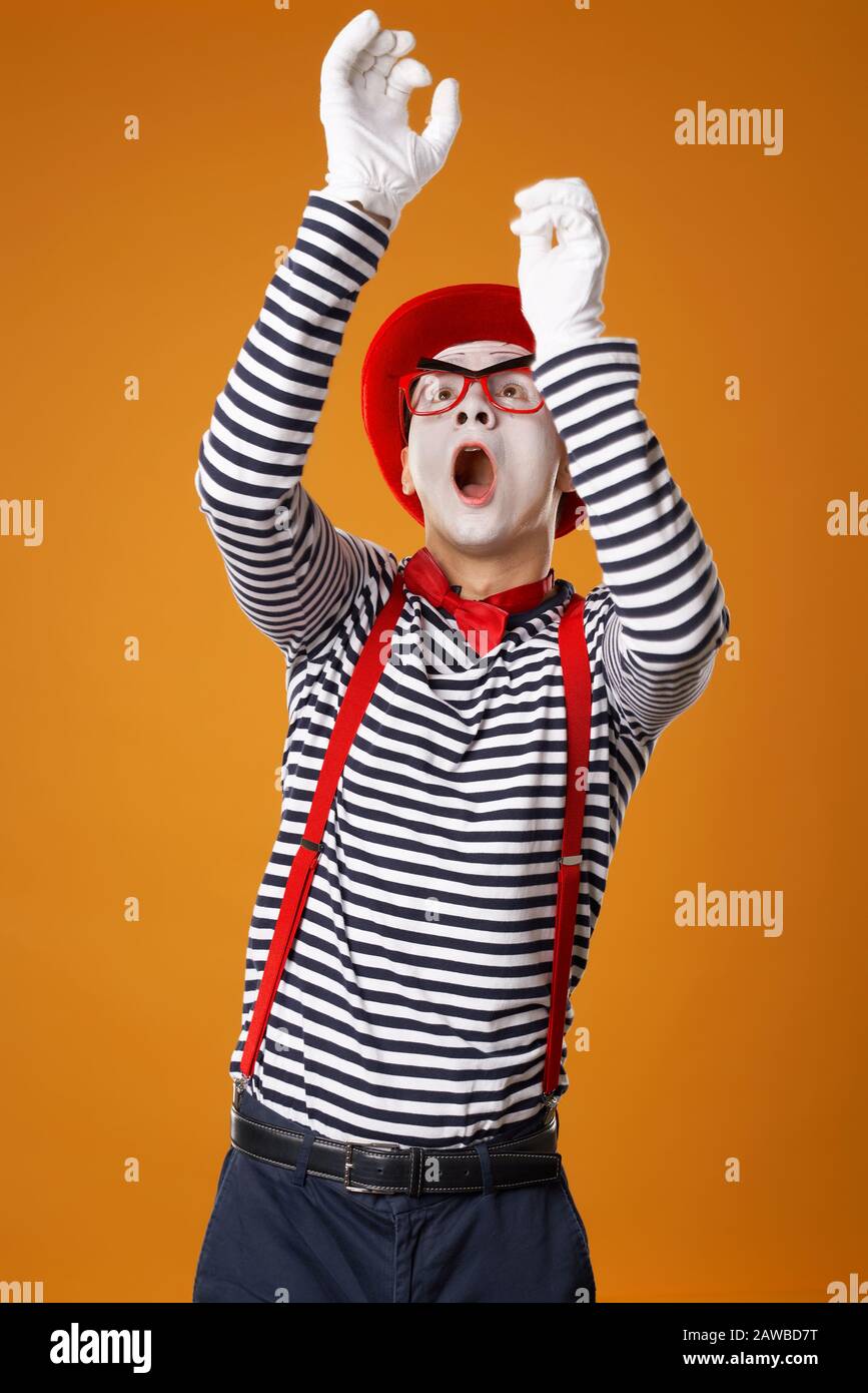 Joven hombre mimo en guantes blancos y sombrero rojo mirando sobre fondo  naranja vacío Fotografía de stock - Alamy
