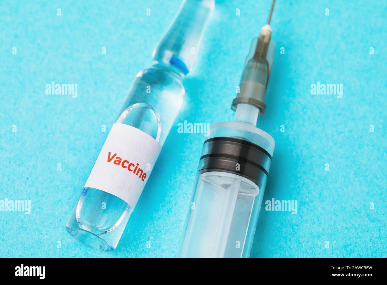 Ampolla con una vacuna contra un virus peligroso y una jeringa sobre fondo azul Foto de stock