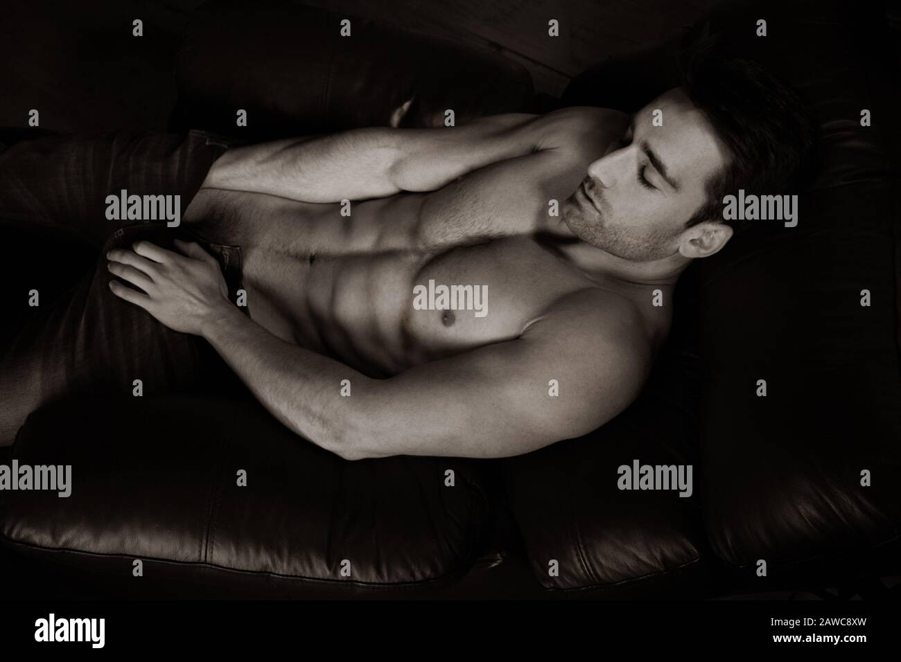 Retrato de un hombre musculoso guapo sin camisa barba y seis paquetes de abs tumbados en un sillón de cuero Fotografía de stock - Alamy