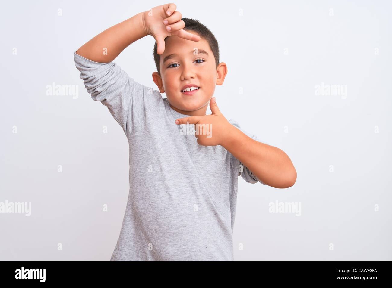 Bonito niño vestido gris sport camiseta de pie sobre fondo blanco aislado  sonriendo hacer marco con las manos y los dedos con cara feliz. Cre  Fotografía de stock - Alamy
