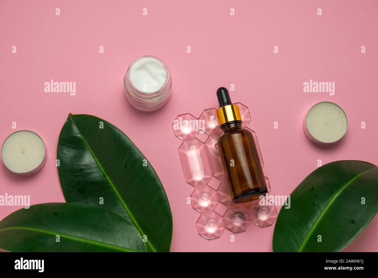 vista superior jarra crema, velas y botella de aceite de aroma en un fondo rosa piel y el concepto de cuidado corporal Foto de stock