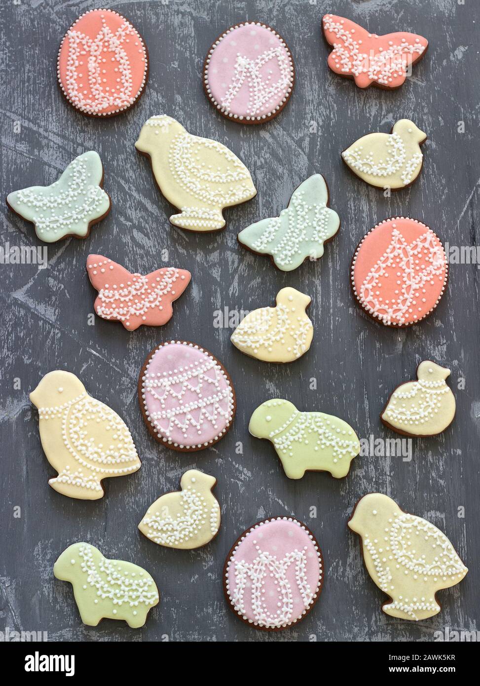 Galletas de pan de jengibre de Pascua decoradas con varios ornamentos sobre un fondo gris. Foto de stock