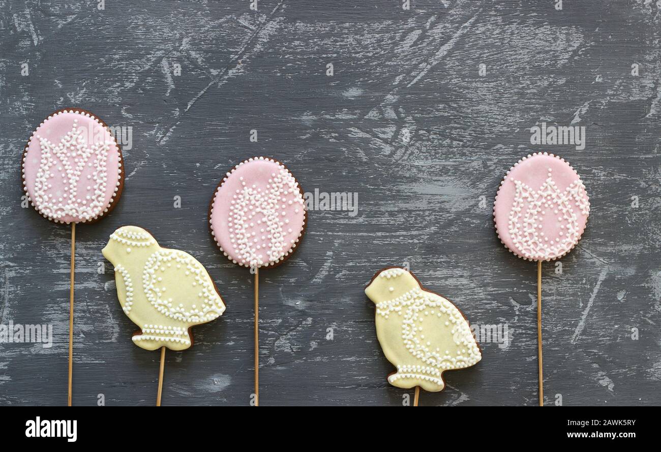 Galletas de pan de jengibre de Pascua decoradas con varios ornamentos sobre un fondo gris. Foto de stock